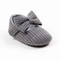 Detail eines grau gerippten gestrickten Babyschuhs mit weicher Textur und großer Schleife - Innenlänge 13cm / Schleife-Stil / Grau