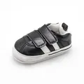 Close-up of black baby walker shoes with white stripes and velcro straps - Black
