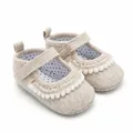 Nahaufnahme von beigen Baby-Mary-Jane-Schuhen mit Pom-Pom-Besatz und Polka-Dot-Futter - Aprikose