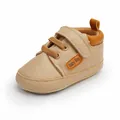 Detailed side view of beige faux leather baby walking shoe with orange accents - Apricot