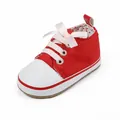 Close-up detail of a red canvas baby walker shoe with a pink ribbon bow and white toe cap. - Inner Length 12cm / Red