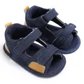 Close-up of navy blue denim baby sandals featuring adjustable velcro strap details. - Dark Blue