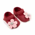 Gros plan de chaussures de princesse tricotées bordeaux pour bébé fille avec fleurs roses - Rouge