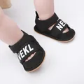 Detailed view of black infant summer sandals with NEKL letter print worn on baby feet - 11cm / Black
