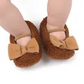 Close-up of brown fuzzy baby slippers featuring a large bow and soft elastic strap detail - Coffee