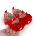Primer plano de zapatos de princesa para bebé en charol rojo con lazo de terciopelo - Rojo