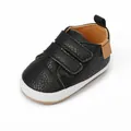 Close-up view of a black faux-leather baby walking shoe with dual Velcro straps - Black