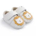 Détail de chaussures de marche blanches pour bébé avec un lion jaune en cartoon. - Blanc