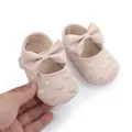 Close-up of pink baby princess shoes featuring large bows and embroidered heart details - Apricot