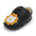 Detailopname van zwart lederen babyschoen met een schattige cartoon van een leeuw - Zwart