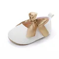 Primer plano de zapato blanco para bebé con un elegante lazo decorativo de satén dorado - Blanco