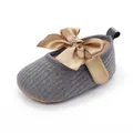 Vista detallada de zapato de bebé de punto gris con un gran lazo decorativo de satén dorado - Gris