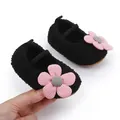 Close-up of black fuzzy baby shoes with pink flower detail and soft sole - Black