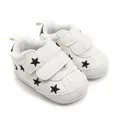 Detail van witte babysneakers met zwarte sterpatronen en handige klittenbandsluiting - Zwarte Sterstijl (1512)