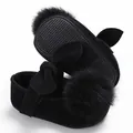 Vue rapprochée de chaussures bébé en velours noir avec pompon doux et nœud - Noir