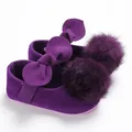 Gros plan de chaussures de princesse violettes pour bébé avec nœud et pompons en fourrure. - Violet
