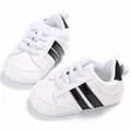 Vista detallada de zapatillas blancas para bebé con rayas negras y suelas blandas - Blanco Negro