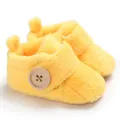Close-up detail of yellow plush baby shoes featuring a large decorative wooden button - 11cm / Yellow