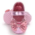 Gros plan de chaussures bébé fille rose métallisé avec nœud et semelle à pois - Rose