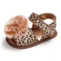 Detailed view of baby leopard print sandal with fluffy brown pom-pom and gold finish. - Bronze