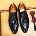 Classic men's black leather brogue oxford shoes on a wooden background with a bow tie. - 37 / Black