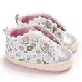 Close-up of baby girl floral shoes with silver glitter toe and scalloped lace trim - Pink