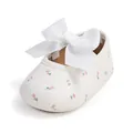 Nahaufnahme von weißen Baby-Prinzessin-Schuhen mit großer Schleife und rosa Blumenmuster - Weiß