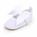 Gedetailleerde weergave van witte baby prinsessenschoenen met een grote satijnen strikdecoratie - Wit