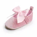 Gedetailleerd overzicht van de roze fluwelen baby prinsessenschoen met satijnen strik - Roze