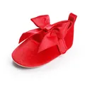 Detailopname van een klassieke rode fluwelen baby prinsessenschoen met een grote satijnen strik - Rood