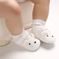 Nahaufnahme weißer gestrickter Babyschuhe mit süßem Tiergesicht und weicher Sohle - Weiß