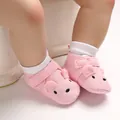 Detaillierte Makroansicht rosa gestrickter Babyschuhe mit Tiergesicht und weicher Sohle für Babys. - Rosa