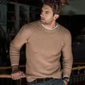 Detailed view of the camel-colored long-sleeve crewneck knit sweater on a male model - S / Tops / Camel