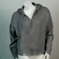 Nahaufnahme des grauen Strick-Cardigans mit Kapuze, Reißverschluss und Fransen-Saum - Grau