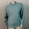 Primer plano de un suéter de punto grueso azul verdoso con cuello alto y mangas de linterna. - Azul claro