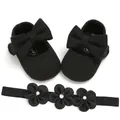 Detail shot of black knit baby princess shoes with big bow and matching floral headband - Black