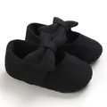 Detail view of black knitted baby walker shoes featuring a large decorative bow on top - Black