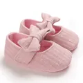 Close-up of pink knitted baby princess shoes with soft soles and large bow details - Pink