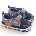 Primo piano di scarpe primi passi in denim blu navy con suole morbide antiscivolo. - Blu
