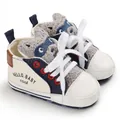 Close-up detail of white baby walking shoe featuring a cute cartoon raccoon tongue - Apricot