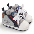 Close-up of grey infant walker shoes with cartoon animal tongue and soft white soles. - Gray