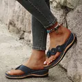 Close-up view of blue wedge flip-flops with laser-cut patterns and flower accents - 35 / Blue