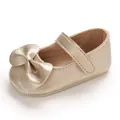 Vue détaillée d'une chaussure de princesse dorée pour bébé fille avec un grand nœud décoratif - Or