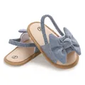 Detalle en primer plano de sandalias de mezclilla azul para bebé con un lazo grande - Azul marino