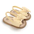 Detalle de sandalias amarillas de bebé con lazos decorativos y tira elástica al talón - Amarillo