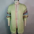 Detail van lichtgroen mohair vest met kleurrijke gestreepte mouwen op een mannequin - Lichtgroen