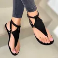 Primer plano de sandalias planas negras de dedo con diseño en T y tachuelas. - Negro
