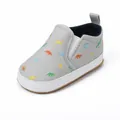 Detailed close-up of grey baby slip-on canvas shoes with colorful dinosaur patterns - Gray