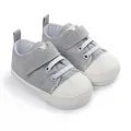 Gros plan de chaussures en toile grises pour bébés avec lacets blancs et embouts de protection - Gris