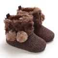 Macro view of brown infant winter boots featuring soft faux fur and pom-poms - Coffee